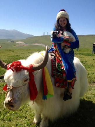 Holding a baby goat while riding a yak in costume -on the way to Qinghai Lake